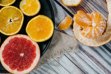 Delicious various types of citrus fruit in plates on wooden background