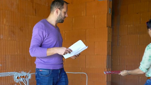 Couple with blueprints checking wall with level at their new house