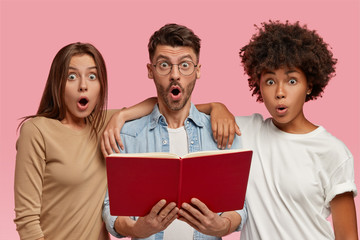 Isolated shot of stupefied three interracial friends prepare for final examamination together, read...