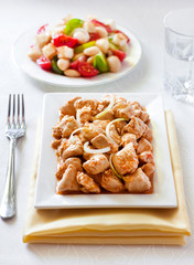 Turkey stew in tomato mustard sauce with onion on square plate