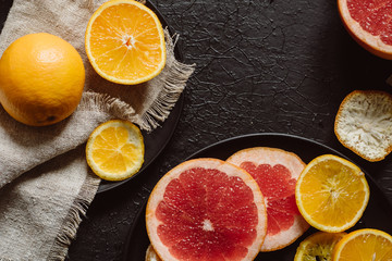 Delicious various types fresh of citrus fruit in plates on dark background