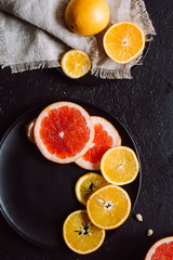 Delicious various types fresh of citrus fruit in plates on dark background