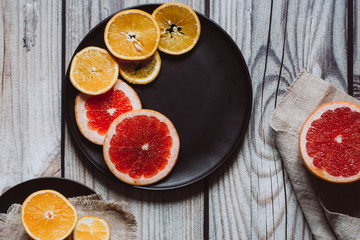Delicious various types of citrus fruit in plates on wooden background