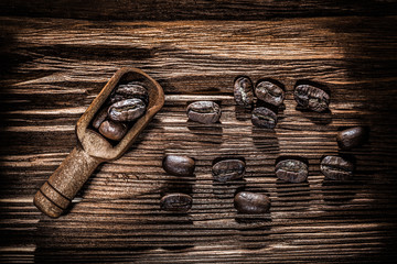 Roasted coffee seeds in scoop on vintage wooden board