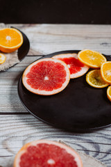 Delicious various types of citrus fruit in plates on wooden background