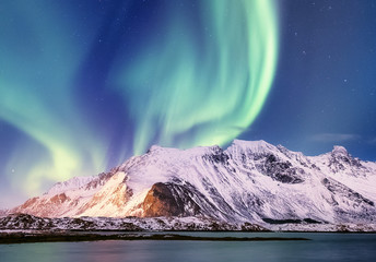 Fototapeta na wymiar Aurora borealis on the Lofoten islands, Norway. Green northern lights above ocean. Night sky with polar lights. Night winter landscape with aurora and reflection on the water surface. 
