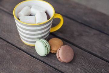 A cup of hot cocoa with marshmallows on a wooden table. Macaroons. Dessert. Breakfast. Cozy. Autumn. Winter.