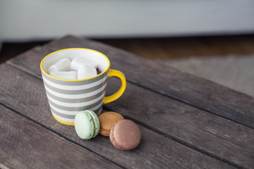 A cup of hot cocoa with marshmallows on a wooden table. Macaroons. Dessert. Breakfast. Cozy. Autumn. Winter.