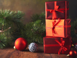 Red gift boxes, fir tree and decoration on wooden background.