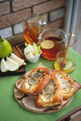French brioche bun with pear, honey and tea on wooden table