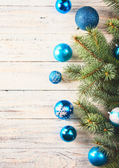 Christmas background. Fir tree and a lot of christmas blue baubles over white wooden board