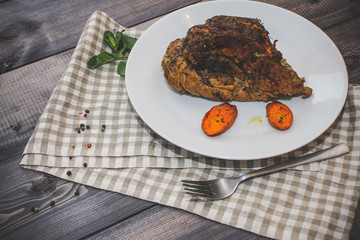 A large piece of baked meat Still life on a light wooden table.