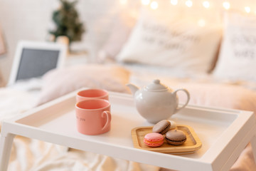 breakfast in bed, tray with cup of coffee and macaroon. Modern bedroom interior. Romantic morning surprise.