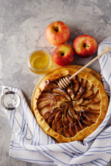 Homemade Apple pie with cinnamon and honey on wooden background.
