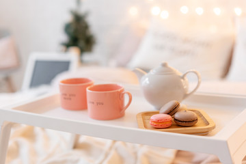 breakfast in bed, tray with cup of coffee and macaroon. Modern bedroom interior. Romantic morning surprise.
