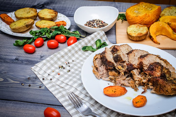 A large piece of baked meat Still life on a light wooden table.