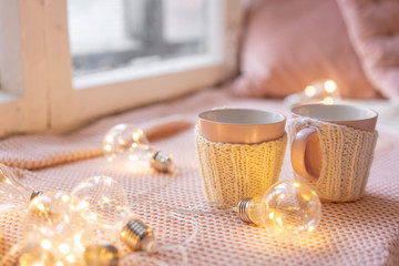 Knitted woolen cups on a wooden table. two cups of hot coffee. the concept of heat. holidays and...