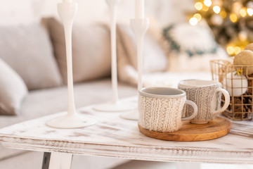Knitted woolen cups on a wooden table. two cups of hot coffee. the concept of heat. holidays and events. Autumn and winter, leisure concept. Cozy, comfy, soft.