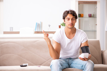 Young man measuring blood pressure at home