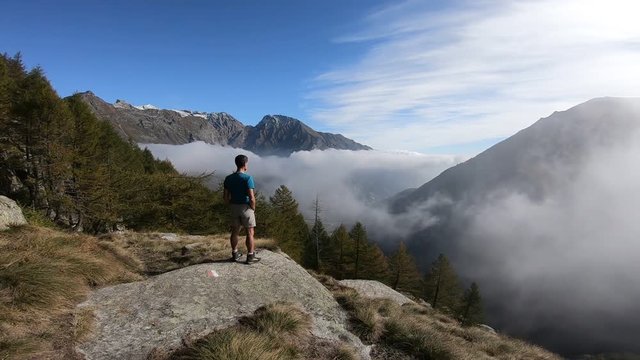 Man on the mountains looking at landscape over the clouds, Gran Paradiso National Park, Italy