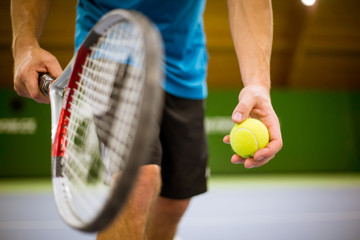 Close-up of male hand holding tennis ball and racket, professional tennis player starting set in the tennis hall