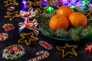 Christmas mood, deer, holiday decor, pine branches and tangerines on dark background.