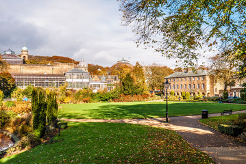 Lovely view of Buxton Park in Autumn, showing the calm pond and beautiful autumnal trees as well as the stone architecture of the town.