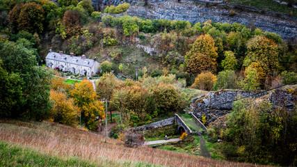 Old stone cottages in the bottom of a dale surrounded by autumn trees on a cloudy day. Taken in the...