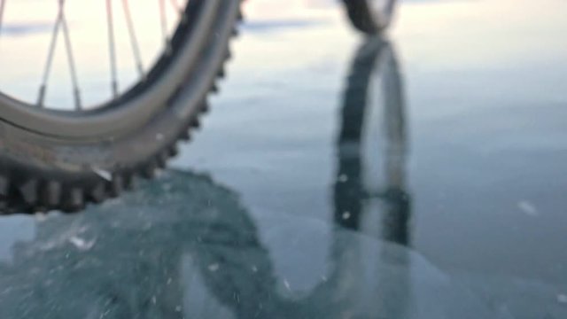View of the tire. Shooting 180fps. Woman is riding bicycle on the ice. Ice of the frozen Lake Baikal. The tires on the bicycle are covered with special spikes. The traveler is ride a cycle.