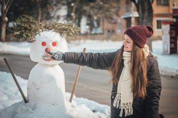 Happy girl touching nose of snowman