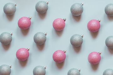 Christmas silver and pink baubles decoration pattern on pastel blue. Minimal flat lay composition.