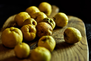 beaux fruits mûrs d'or jaune d'un coing sur une planche de bois sur un fond noir