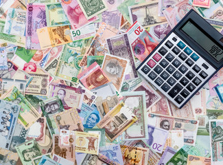 Calculator on mixed banknotes background, close up