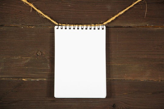 Paper mock up old notebook on a rope on a black wooden board. Place for text. Copy space. Place for announcements.