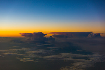 Fototapeta na wymiar Thunderstorm clouds illuminated during sunset - inflight view 