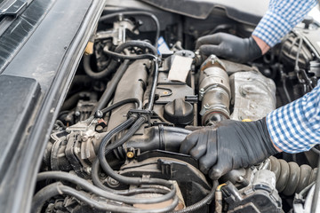 Fototapeta na wymiar Car engine with worker's hands in gloves