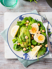 Avocado spinach salad with chickpeas and hard boiled eggs served on a dish. Fats and proteins