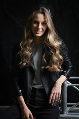 Fototapeta na wymiar Beautiful girl with long curly hair in black leather jacket, t-shirt and jeans