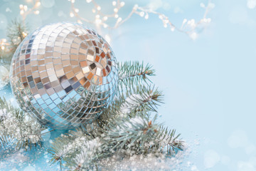 Christmas mirror evening ball with fir tree and garland on pastel blue. Holiday card with copy space.