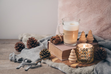 Hygge Scandinavian style concept with latte macchiato coffee cup, candles and book