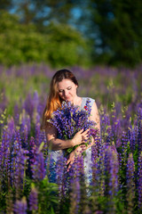A beautiful girl is standing in a lupine field.