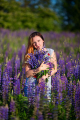 A beautiful girl is standing in a lupine field.