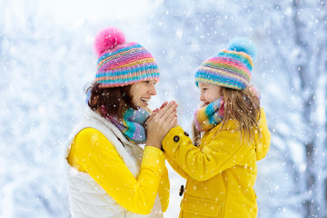 Mother and child in knitted winter hats in snow.