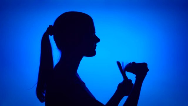 Silhouette of young successful woman count bundle of money on blue background. Female's face in profile with pile of bills. Black contur shadow of teenager's half-face. Concept of wealth and success