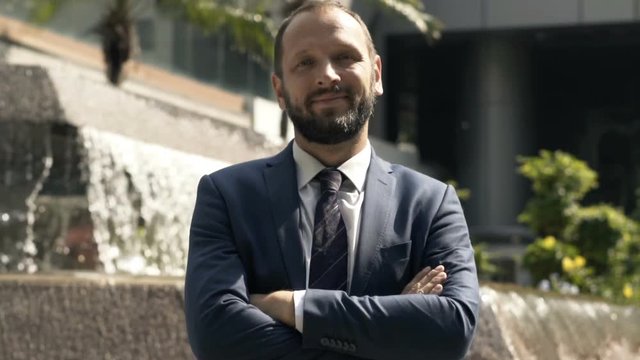 Portrait of happy, young businessman standing near fountain in city