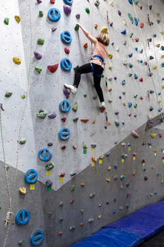 Chubby pretty Caucasian girl climbering artificial rock-climbing walls