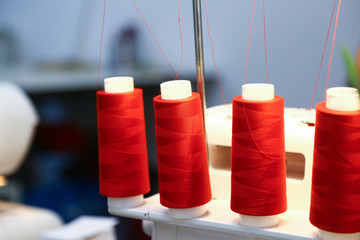 red yarn spools on a white sewing-machine in a tailor´s studio