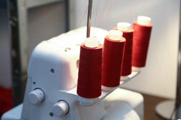 red yarn spools on a white sewing-machine in a tailor´s studio