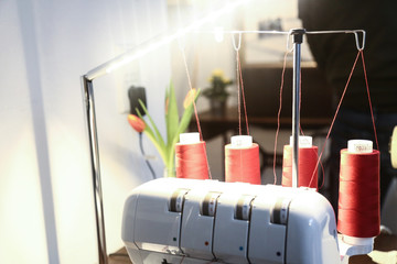 red yarn spools on a white sewing-machine in a tailor´s studio