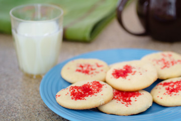Traditional Butter cookies on blue plate with glass of milk.